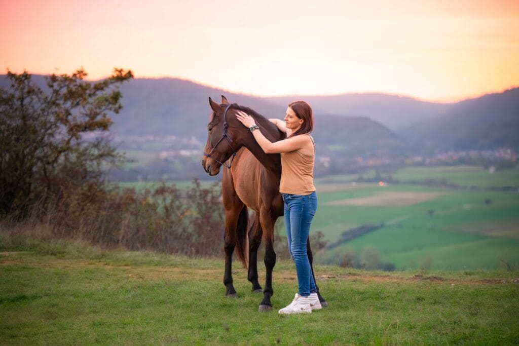 Praticienne bien-être animal manipulant doucement un cheval pour lui redonner de l'énergie