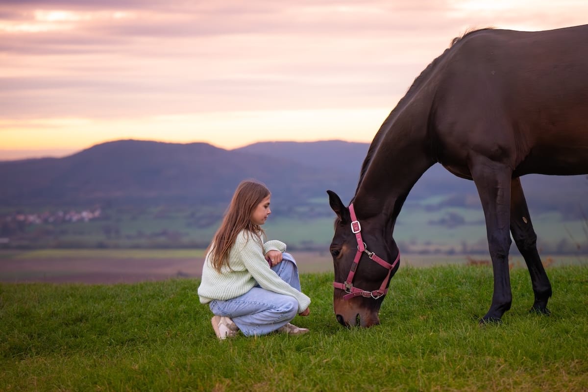 Cheval broutant paisiblement près d'une jeune fille